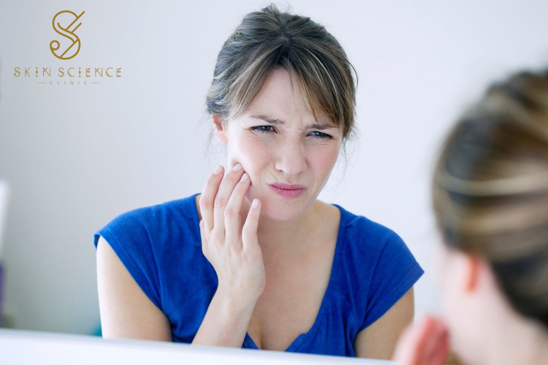 A woman holding her jaw in discomfort from bruxism